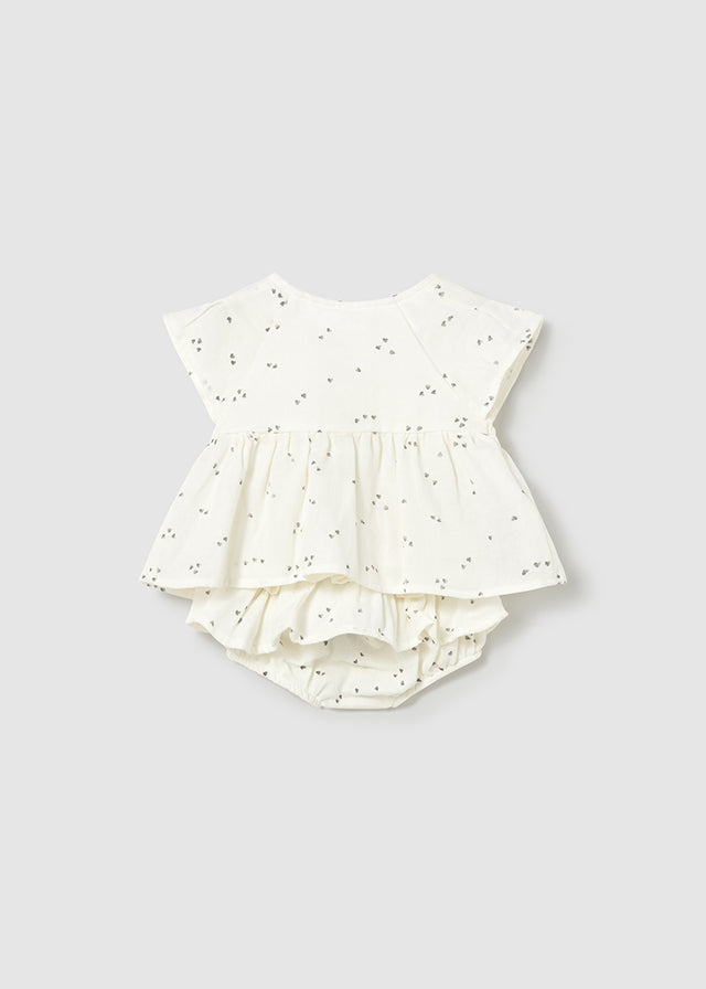 Baby outfit with top and ruffled bloomers on a light gray background