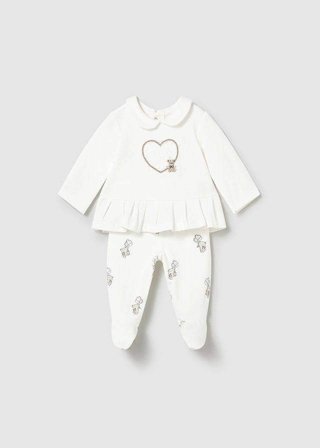 White baby outfit with a heart design on a light gray background