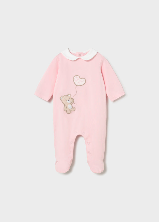 Pink baby onesie with teddy bear and heart design on a light gray background