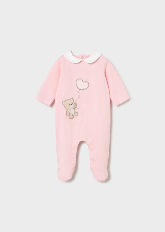 Pink baby onesie with teddy bear and heart design on a light gray background