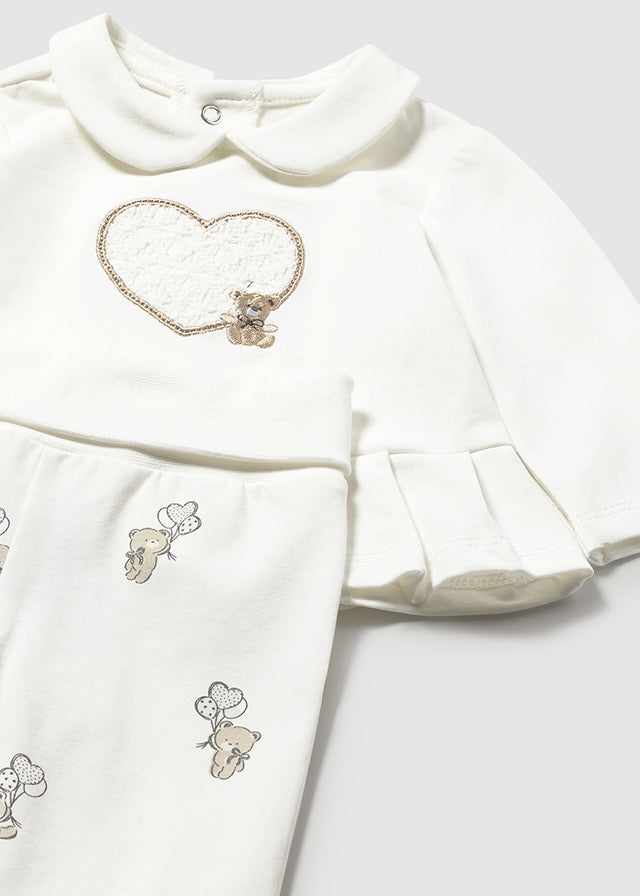 White baby dress with embroidered teddy bears and heart design on a light gray background