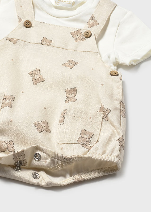Baby outfit with beige overalls featuring teddy bear patterns on a white background