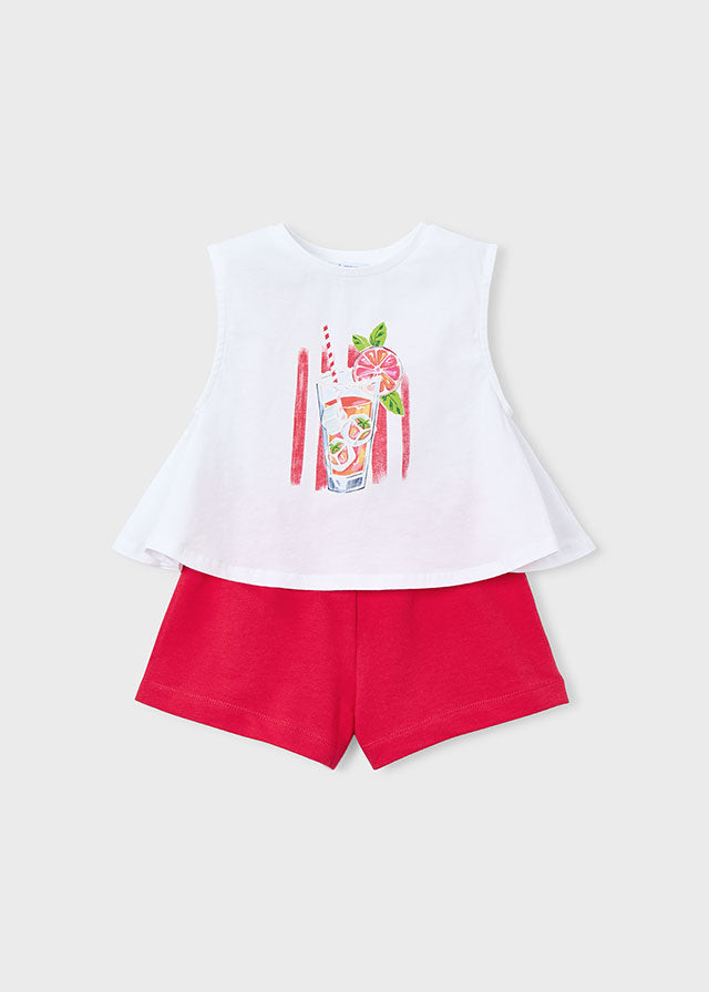 White sleeveless top with a graphic design and red shorts on a light gray background