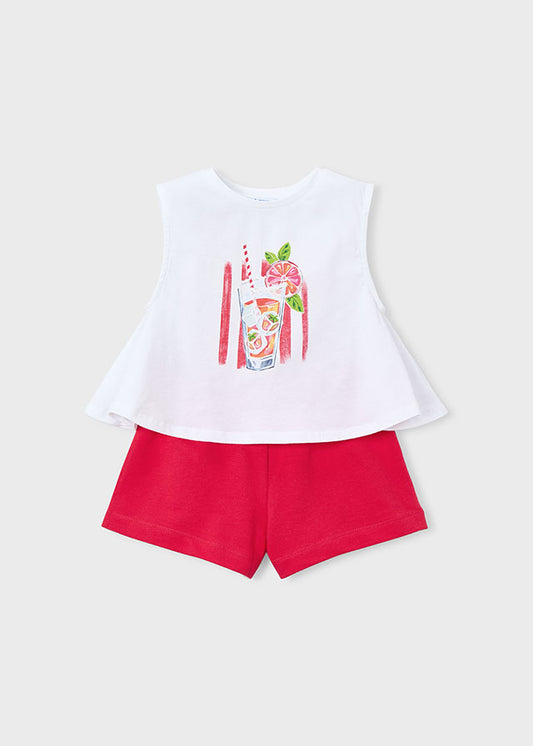 White sleeveless top with a graphic design and red shorts on a light gray background
