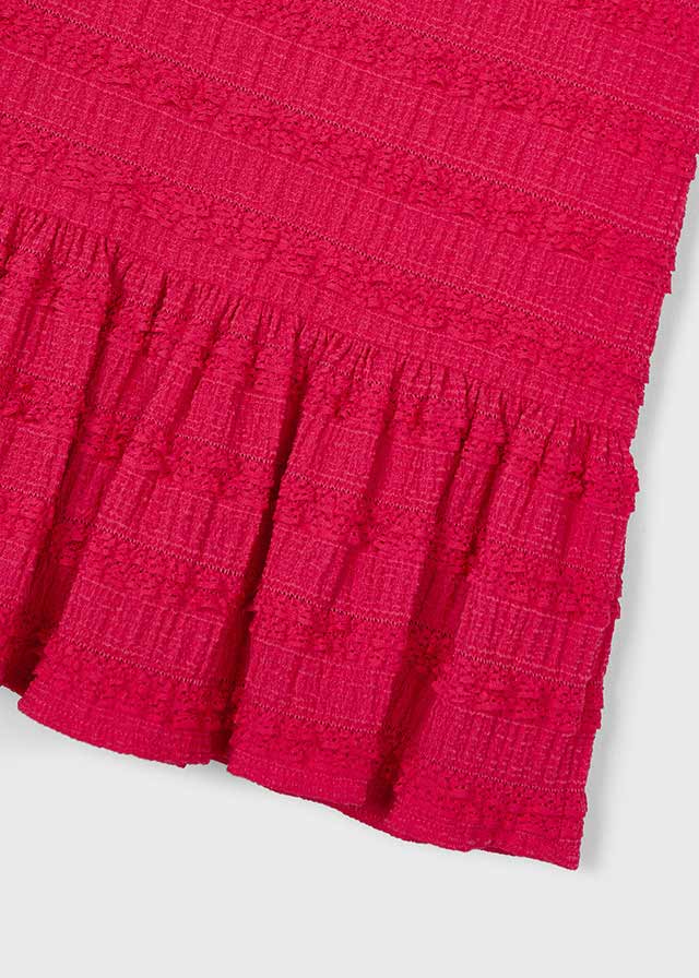 Close-up of a red textured fabric with ruffled edge on a white background