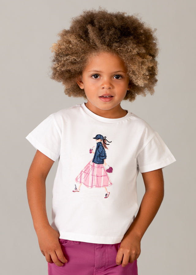 Contemporary girls’ t‑shirt featuring a fashion‑forward illustration of a stylish woman in streetwear (pink skirt, denim jacket, accessories).