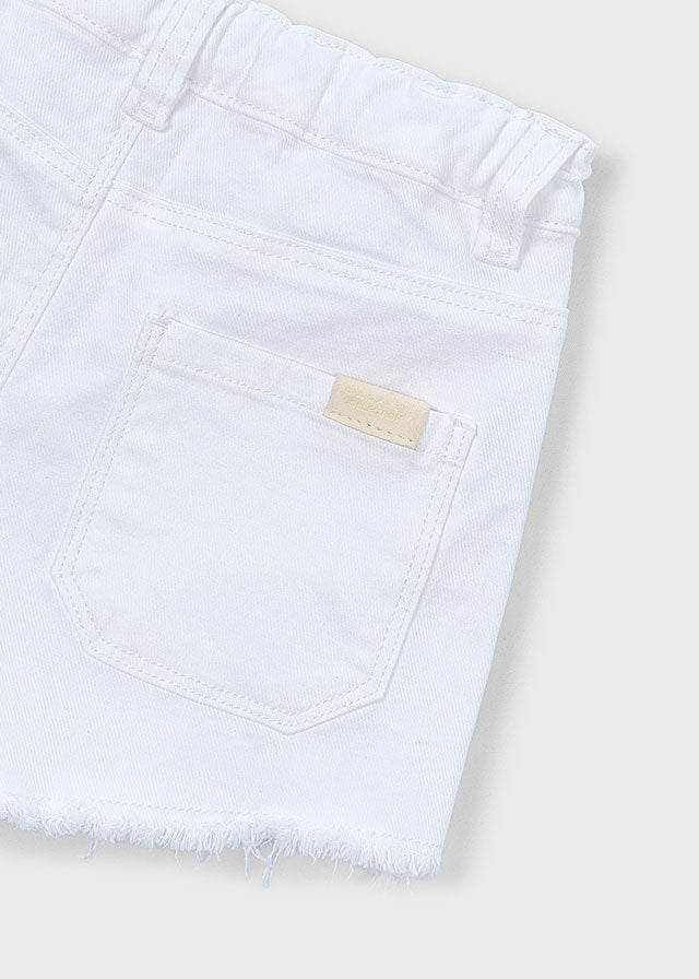 Close-up of a white denim pocket with a brand label on a light background